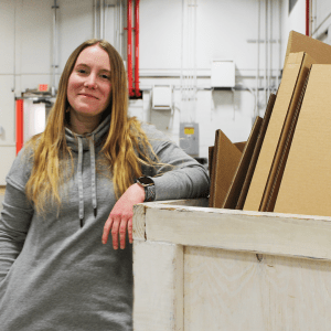 Hannah practices sustainability in the workplace and dumps corrugated scrapes into the bin.